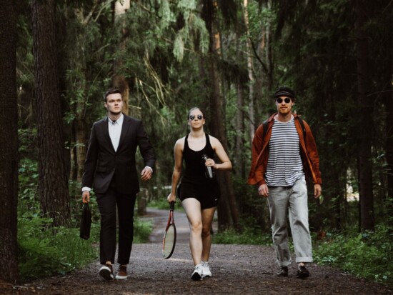 Kolme ihmistä kävelyllä Helsingin keskuspuistossa kesällä