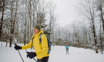 Vanhempi mies hiihtää hiihtoladuilla metsän keskellä Helsingissä